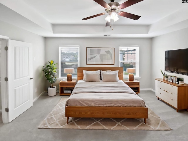 bedroom featuring baseboards, a tray ceiling, and a ceiling fan