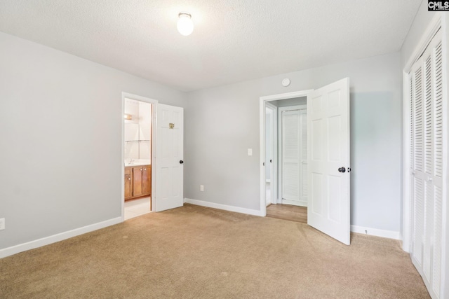 unfurnished bedroom with light carpet, a closet, baseboards, connected bathroom, and a textured ceiling