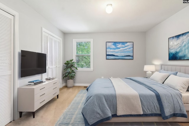 bedroom with light colored carpet, baseboards, and two closets