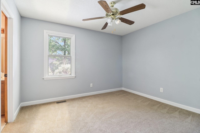 spare room featuring light carpet, baseboards, and a ceiling fan