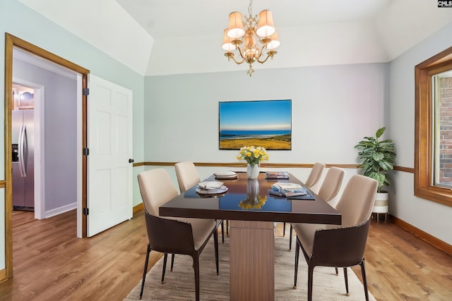 dining space featuring light wood-style flooring, baseboards, a chandelier, and lofted ceiling