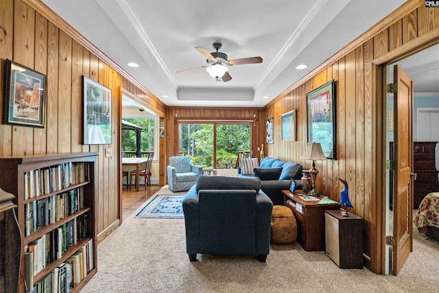 4833 Circle Dr, Columbia, SC 29206 - living room featuring light carpet, wood walls, a ceiling fan, ornamental molding, and a tray ceiling