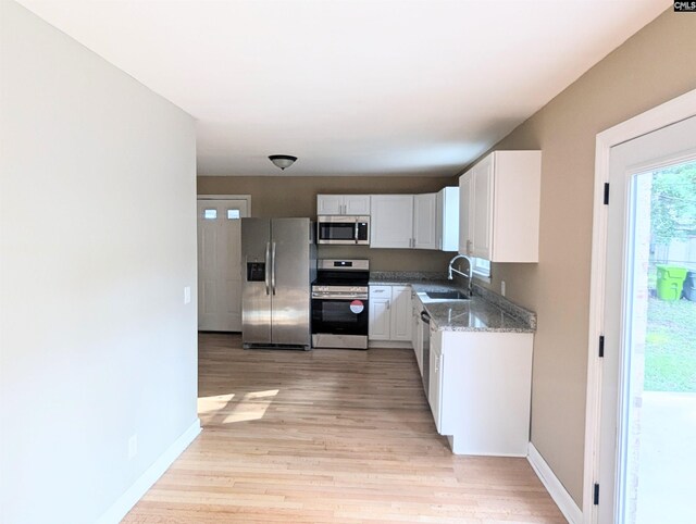 1921 Spotswood Dr, Columbia, SC 29210 - kitchen with stainless steel appliances, a sink, light wood-style flooring, and white cabinets