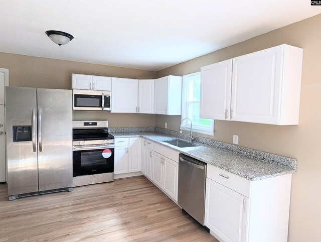 1921 Spotswood Dr, Columbia, SC 29210 - kitchen featuring stainless steel appliances, a sink, white cabinetry, light wood-type flooring, and light stone counters