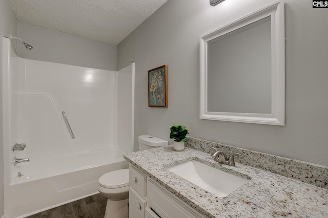 bathroom featuring toilet, wood finished floors, bathing tub / shower combination, a textured ceiling, and vanity