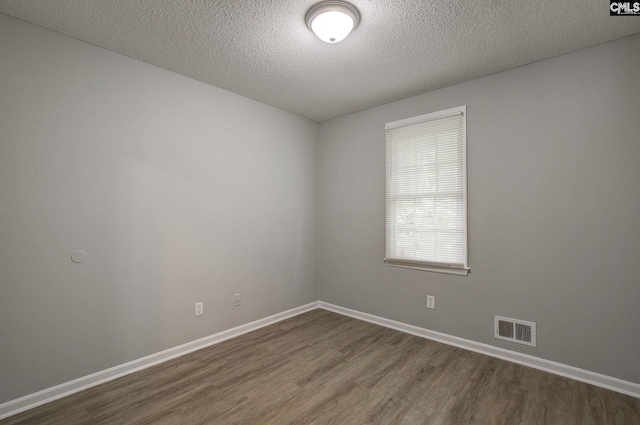 empty room featuring dark wood-style floors, a textured ceiling, and baseboards