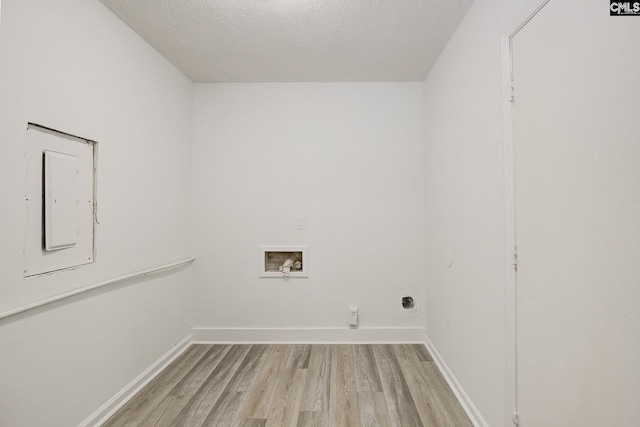 clothes washing area with hookup for a washing machine, light wood-type flooring, a textured ceiling, hookup for an electric dryer, and baseboards