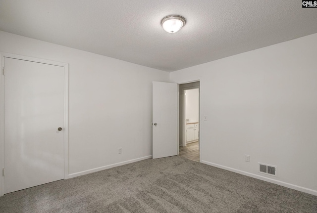 unfurnished bedroom featuring carpet, baseboards, and a textured ceiling