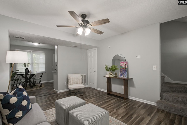 living area with wood finished floors, ceiling fan, baseboards, and stairway