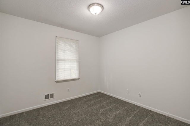 spare room with dark colored carpet, baseboards, and a textured ceiling