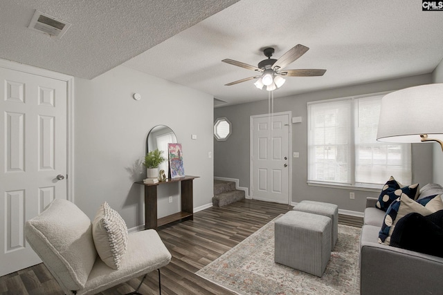 living room with wood finished floors, a textured ceiling, baseboards, ceiling fan, and stairway