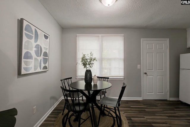 dining room featuring dark wood-style flooring, a textured ceiling, and baseboards