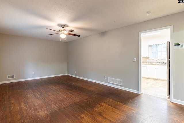 spare room with a ceiling fan, dark wood-type flooring, baseboards, and a sink