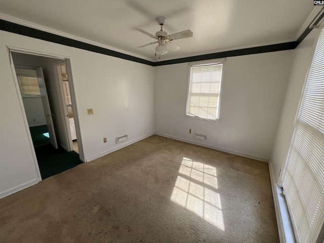 carpeted spare room with crown molding, ceiling fan, and baseboards