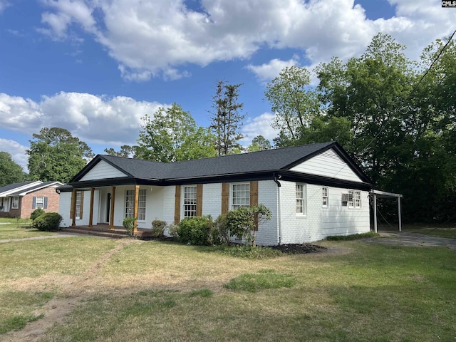 ranch-style home featuring covered porch, brick siding, a front yard, and an attached carport