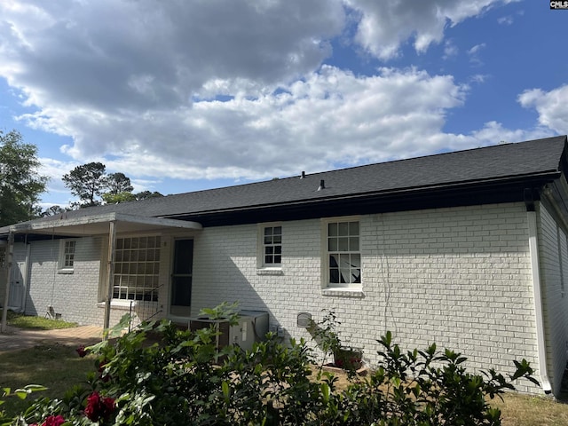 rear view of house featuring brick siding and a shingled roof