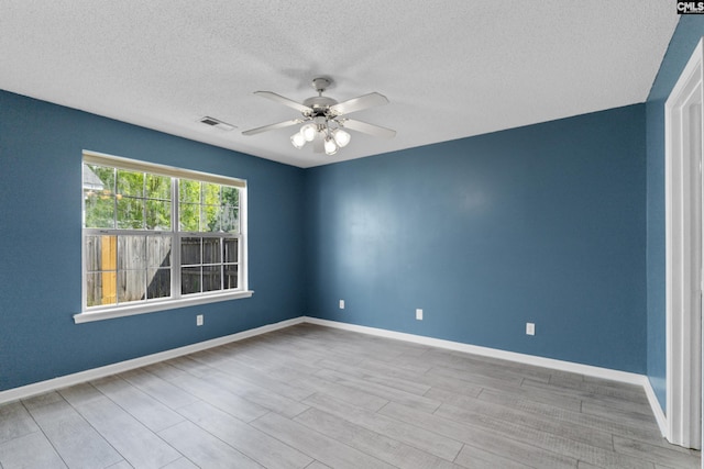 spare room featuring a textured ceiling, a ceiling fan, wood finished floors, and baseboards
