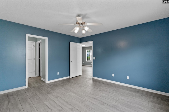 unfurnished room featuring a ceiling fan, baseboards, wood finished floors, and a textured ceiling