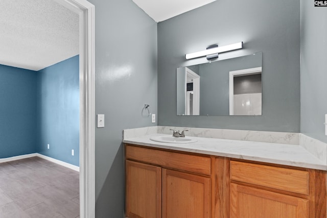 bathroom with vanity, baseboards, and a textured ceiling