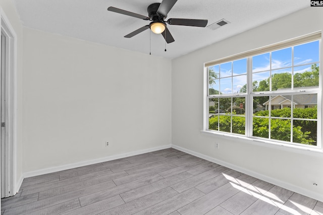 empty room featuring wood finished floors, baseboards, and ceiling fan
