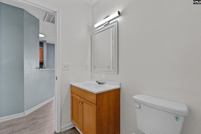 bathroom with baseboards, vanity, toilet, and wood finished floors