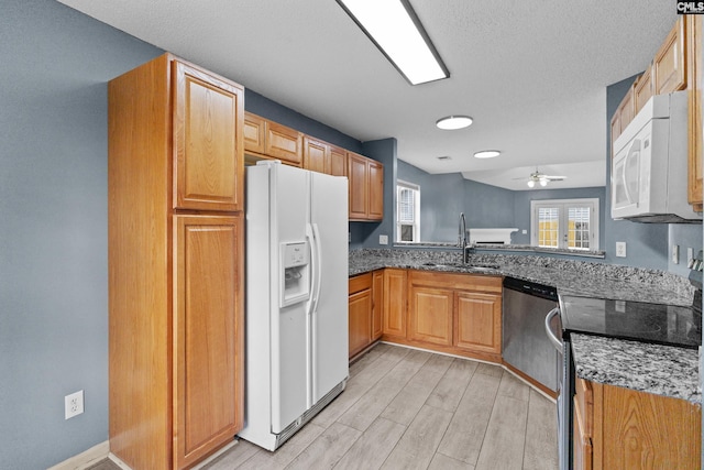 kitchen with appliances with stainless steel finishes, a sink, a ceiling fan, and dark stone counters