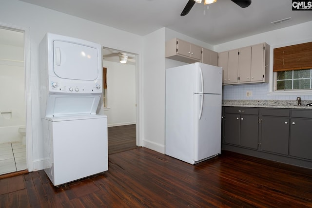 808 Oak St, Columbia, SC 29205 - kitchen featuring freestanding refrigerator, stacked washing machine and dryer, a ceiling fan, dark wood finished floors, and gray cabinetry