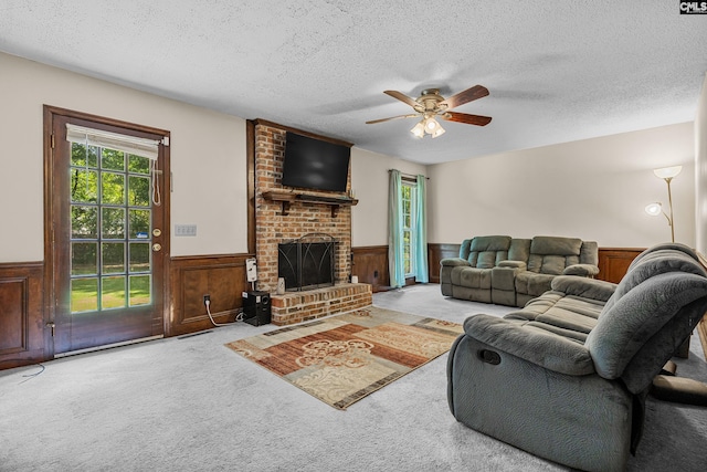 401 Brickling Rd, Irmo, SC 29063 - living area with a wainscoted wall, a textured ceiling, a ceiling fan, a brick fireplace, and carpet flooring