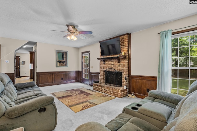 401 Brickling Rd, Irmo, SC 29063 - living area featuring wainscoting, a textured ceiling, carpet, a ceiling fan, and a brick fireplace