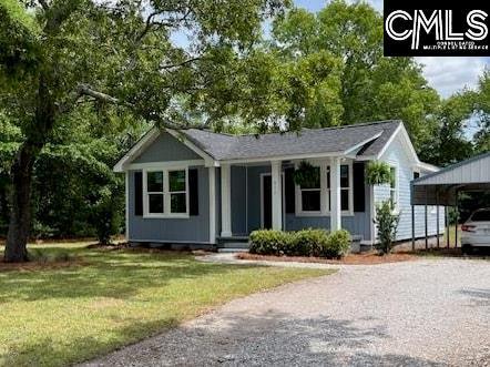 ranch-style home with a front yard, driveway, and a detached carport