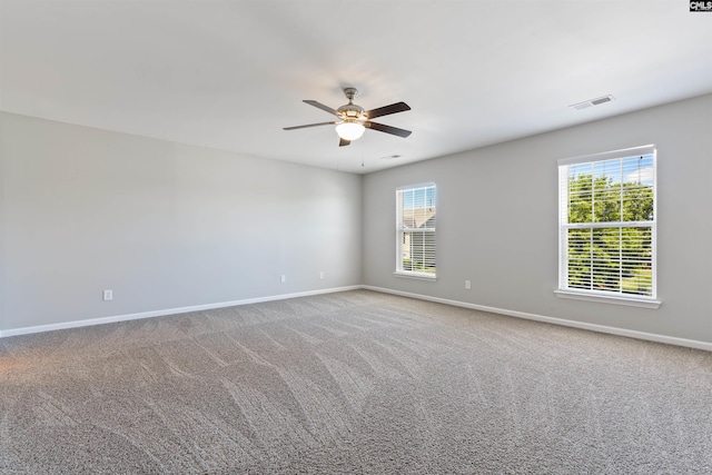 carpeted empty room featuring baseboards, a ceiling fan, and healthy amount of natural light