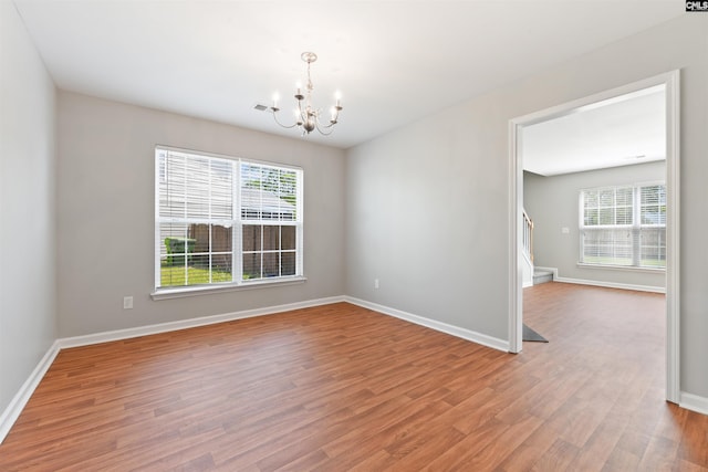 unfurnished room with a chandelier, wood finished floors, and baseboards