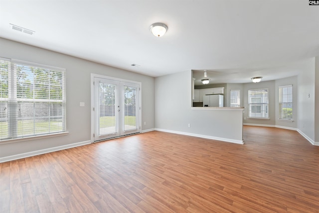 unfurnished living room featuring plenty of natural light, wood finished floors, and baseboards