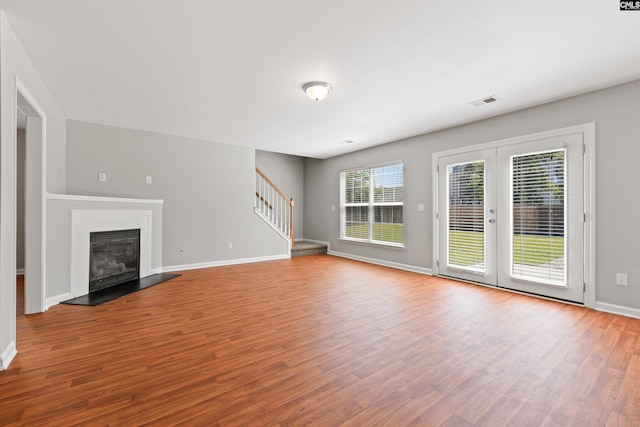 unfurnished living room with wood finished floors, stairway, and baseboards