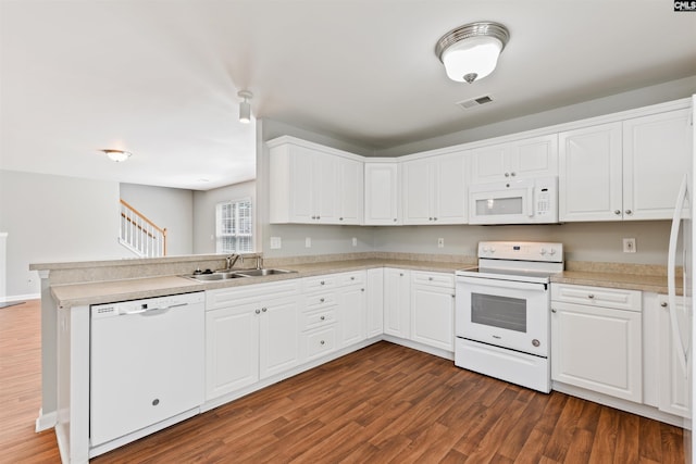 kitchen featuring white appliances, a sink, a peninsula, and dark wood-type flooring