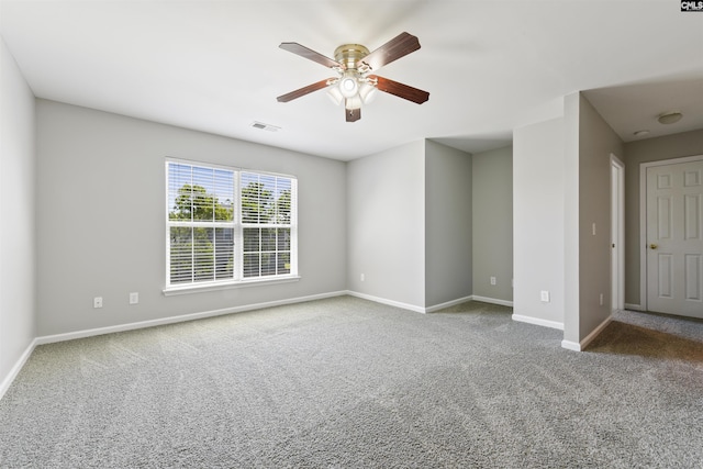 carpeted spare room featuring a ceiling fan and baseboards