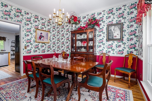 dining room with wallpapered walls, a wainscoted wall, wood finished floors, a chandelier, and ornamental molding