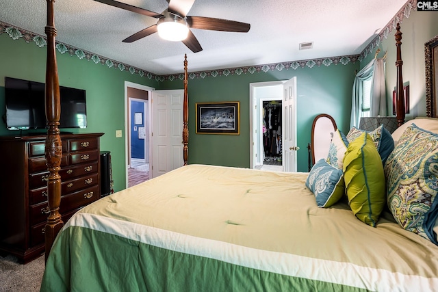 bedroom featuring a spacious closet, a textured ceiling, carpet floors, ceiling fan, and a closet