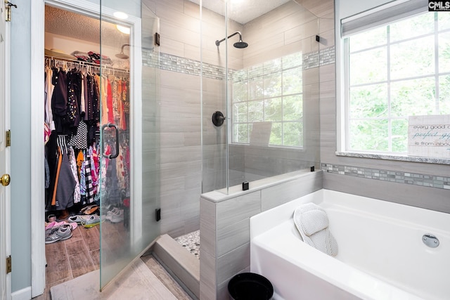full bathroom with a shower stall, a bath, and a walk in closet