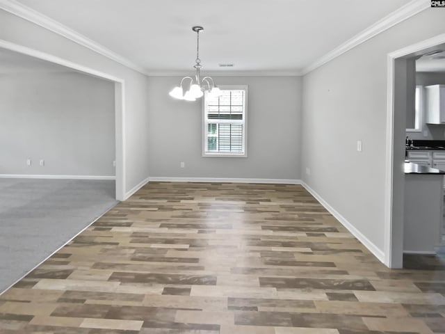 unfurnished dining area with a chandelier, baseboards, wood finished floors, and ornamental molding