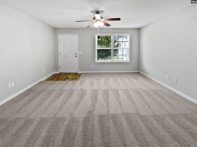 carpeted empty room featuring ceiling fan and baseboards