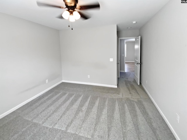 carpeted spare room with a ceiling fan and baseboards