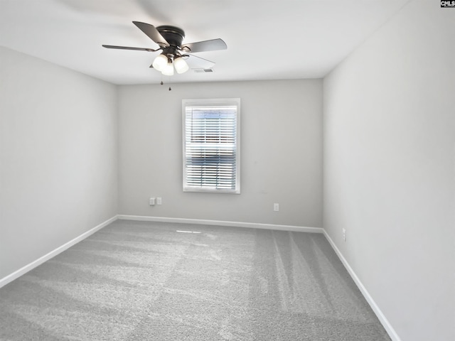 carpeted spare room with a ceiling fan and baseboards