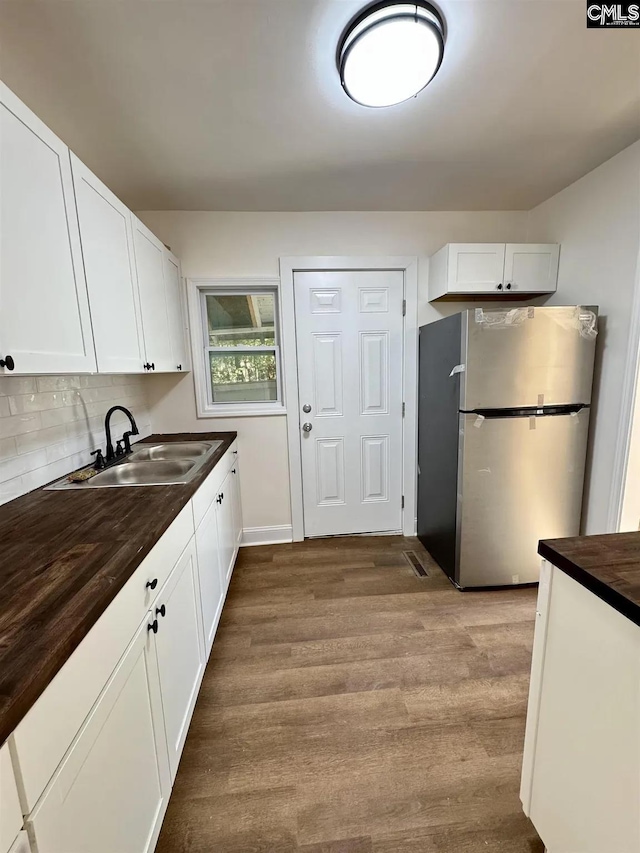 1306 Bonner Ave, Columbia, SC 29204 - kitchen featuring freestanding refrigerator, a sink, white cabinetry, and wood finished floors