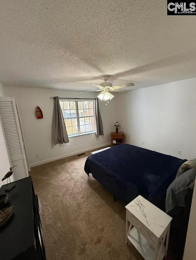 bedroom with a textured ceiling, a ceiling fan, carpet flooring, and baseboards