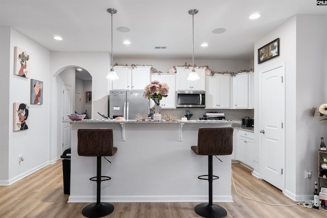 603 Rose Quartz Ln, Lexington, SC 29073 - kitchen featuring appliances with stainless steel finishes, arched walkways, a kitchen bar, light wood-type flooring, and recessed lighting