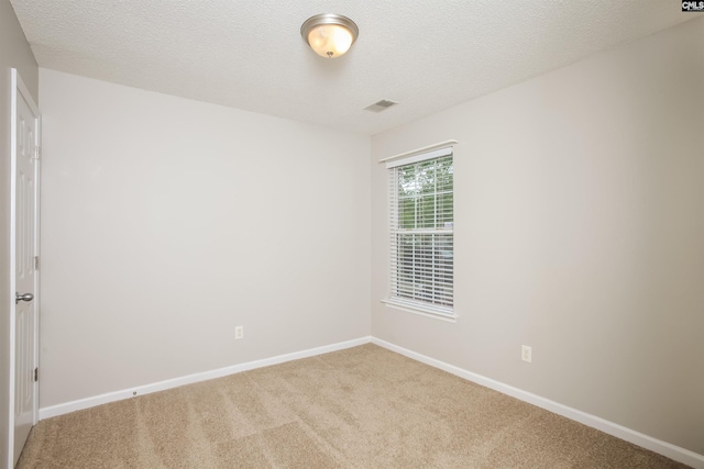 spare room featuring carpet floors, baseboards, and a textured ceiling