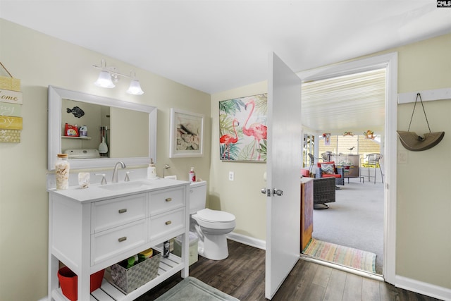 bathroom featuring toilet, wood finished floors, vanity, and baseboards