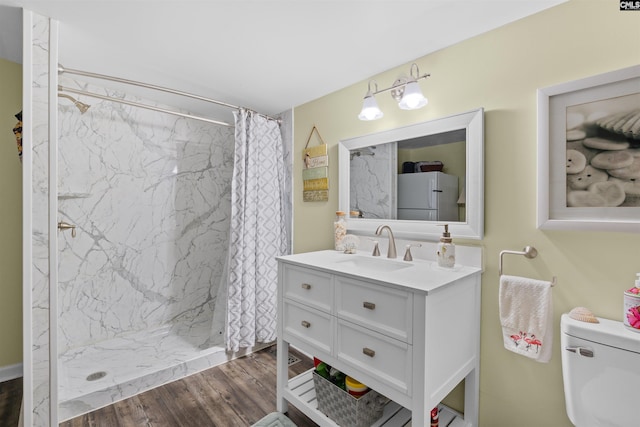 full bathroom with a shower stall, wood finished floors, vanity, and toilet