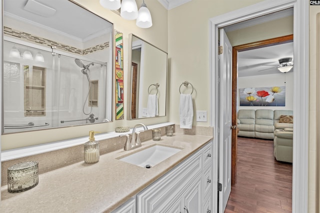 full bathroom featuring crown molding, a shower with shower door, a ceiling fan, vanity, and wood finished floors